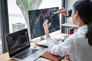 Student analyzing financial and economic data on multiple computer screens.